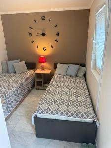 two beds in a room with a clock on the wall at Dolina Ruža in Bogutovac