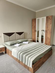 Un dormitorio con una cama grande con cabecero de madera. en Your Comfort, en Kutaisi