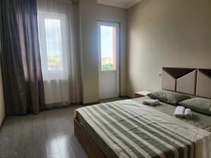 Un dormitorio con una cama y dos grandes ventanales. en Your Comfort, en Kutaisi