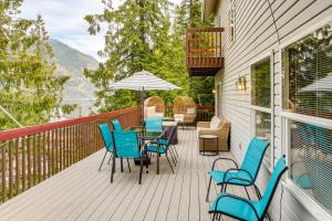 a deck with chairs and tables and an umbrella at Fish and Bike Lake Pend Oreille Gem with Hot Tub! in Athol