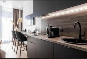 a kitchen with a sink and a counter with chairs at Преміальні апартаменти на березі озера Молодості in Bukovel