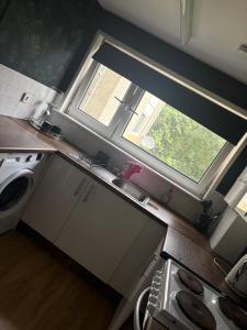 a small kitchen with a window and a sink at Modern 1 bedroom flat full flat in East Kilbride