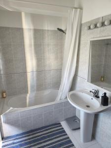 ein Badezimmer mit einer weißen Badewanne und einem Waschbecken in der Unterkunft Praca e Canto in Amoreira