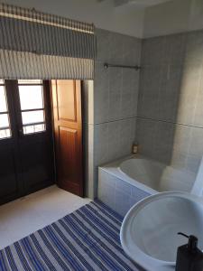 ein Badezimmer mit Badewanne und Waschbecken und einer Tür in der Unterkunft Praca e Canto in Amoreira + 13 Fotos