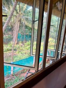 a window with a view of a palm tree at Wood House Near Isha And Karunya University by Shivalaya in Alāndurai