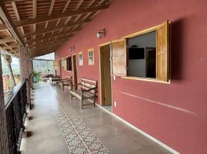 a room with a red wall with chairs and a window at Pousada e Pub Chalé do Rock in São João Batista do Glória