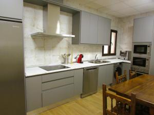 a kitchen with white cabinets and a sink and a table at Casa Rural El Parque in Navalcán