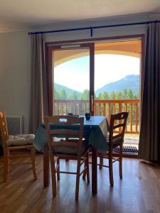 a dining room with a table and chairs and a balcony at Granges d'Arvieux, Splendide T2, Rdc, Vue dégagée in Arvieux