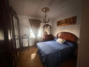 een slaapkamer met een bed met een blauw dekbed en een raam bij Casa campo de 3 habitaciones con parcela in Villamayor +39 foto's
