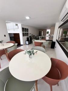 a dining room with tables and chairs and a kitchen at Villa moderna con piscina y espacios sociales in Cali