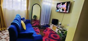 a living room with a blue couch and a tv at Ndune Homes in Isiolo