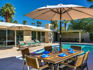 a wooden table with an umbrella next to a pool at Movie Colony Palms by ACME House Company in Palm Springs