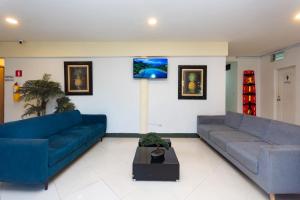 a living room with two blue couches and a table at Hotel Villa Real 70 Laureles in Medellín