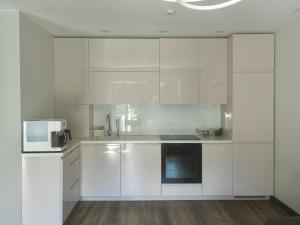 a white kitchen with white cabinets and appliances at Hipodromo street Palanga in Palanga