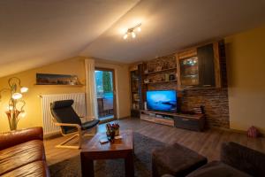 Una sala de estar con un sofá y un televisor. en Haus im Oberland FeWo Berg, en Bad Kohlgrub