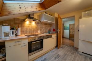 cocina con electrodomésticos blancos y suelo de madera en Haus im Oberland FeWo Berg, en Bad Kohlgrub