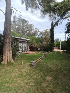 ein Park mit einem Baum und Bänken im Gras in der Unterkunft Cuatro estaciones - Casa en PuntaNegra in Barra de Portezuelo