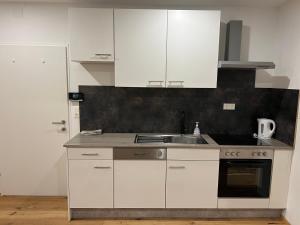 a kitchen with white cabinets and a sink at Main Square Loft Apartment for 6 in Wiener Neustadt