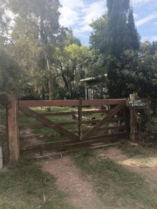ein Holztor auf einem Feld mit Bäumen in der Unterkunft Cuatro estaciones - Casa en PuntaNegra in Barra de Portezuelo