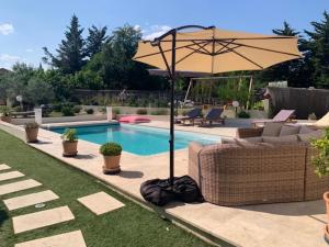 a pool with an umbrella and chairs and a patio at Mas des Clôts in Lavilledieu