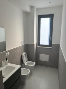 a bathroom with a toilet and a sink and a window at Levante Casa Vacanze 2 in Torrenova +3 photos