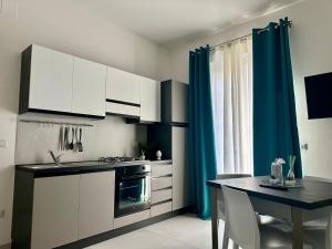a kitchen with white cabinets and a table and blue curtains at Levante Apartments in Torrenova