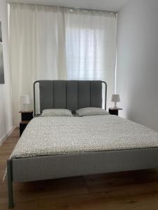 a bed in a white room with two lamps at Saga in Piotrków Trybunalski