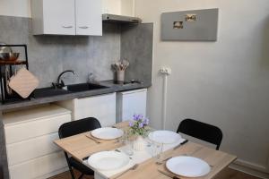 a kitchen with a wooden table with chairs and a sink at L'écho de Saint-Michel - Dijon in Dijon