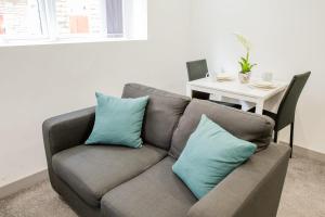 a couch with blue pillows in a living room at Cosy 1 Bedroom Apartment in Central Blackburn in Blackburn