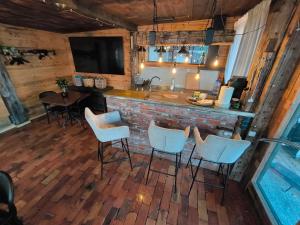 a bar in a log cabin with chairs and a tv at Buļļi atpūtas vieta in Gūžas