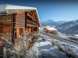 une cabane en rondins dans la neige avec des montagnes en arrière-plan dans l'établissement Chalet Cashmere Spirit - OVO Network, à Manigod