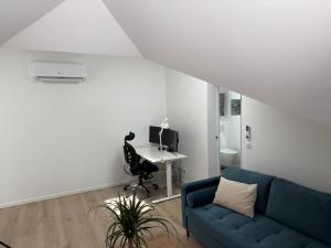 a living room with a blue couch and a desk at Dépendance près de Fontainebleau in Vulaines-sur-Seine