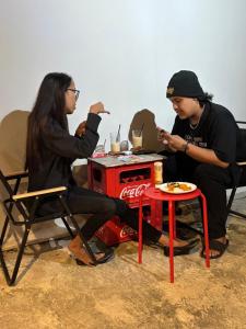 two people sitting at a table with a soda machine at Upi Home BnB Malioboro in Yogyakarta