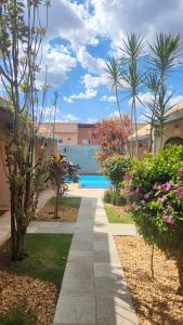 a walkway through a garden with palm trees and a pool at Loft Aconchegante in Pirenópolis