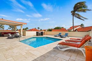 a patio with a pool and chairs and a palm tree at Mesa Vista 36 Tierra del Sol in Noord