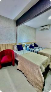 um quarto com 2 camas e uma cadeira vermelha em Apto próximo à praia da Barra, com vista para o mar! em Salvador