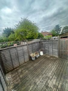 a wooden deck with three potted plants on it at Comfortable cosy one bed flat with garden in se London in Elmers End