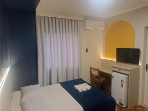 a bedroom with a bed and a desk with a television at Soratur Hotel & Coworking in Criciúma