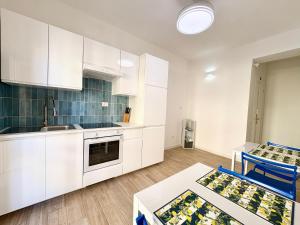 a kitchen with white cabinets and blue tiles at B&B Salty Mermaid in Tropea