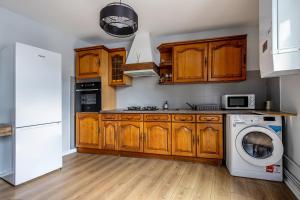 a kitchen with wooden cabinets and a washing machine at Chez Ismarita & Jérôme - Tout Dax à pied - Wifi in Dax