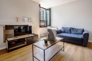 a living room with a blue couch and a tv at Chez Ismarita & Jérôme - Tout Dax à pied - Wifi in Dax