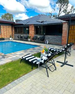 two lounge chairs sitting next to a swimming pool at Hope Villa Luxury Accomodation in Odendaalsrus
