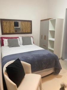 a bedroom with a large bed and a chair at Alugo suites mobiliado centro com áreas sociais Picina in Araguaína +15 photos