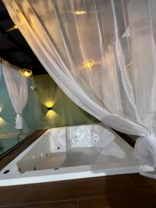 a white bath tub in a room with curtains at Casa Aconchegante Saboto in Foz do Iguaçu +22 photos