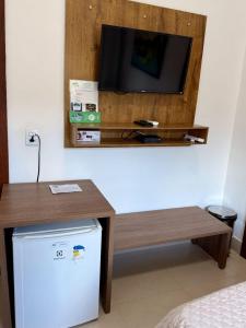 a room with a tv and a table and a refrigerator at POUSADA RECANTO DAS VERTENTES in Capitólio
