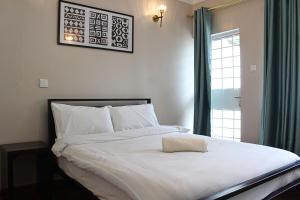 a bedroom with a large white bed with a window at Charming 3-Bedroom Townhouse with Garden & Balcony - Lavington, Nairobi in Nairobi