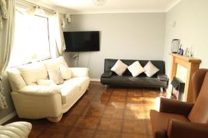 a living room with a white couch and a black chair at Galleywood House in Great Baddow