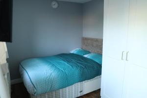 a small bedroom with a bed with blue sheets at Galleywood House in Great Baddow