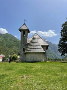 an old building in a field with mountains in the background at Thethi Mountain guesthouse in Theth