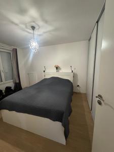 a bedroom with a black and white bed and a chandelier at La maison des vacances in Saint-Thibault-des-Vignes
